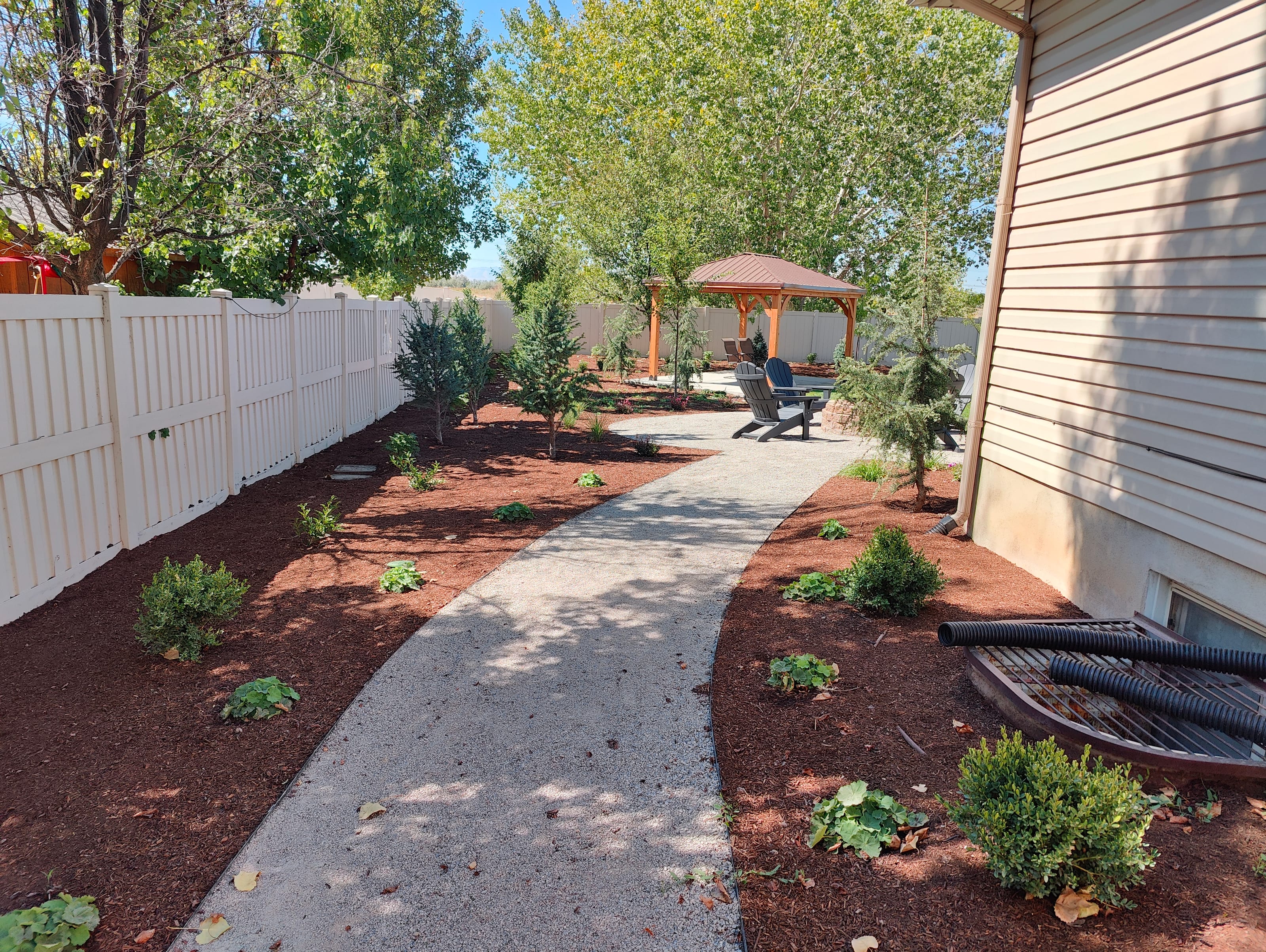 Utah side yard water-wise landscaping with pebble walkway, mulch beds, and low-water plants
